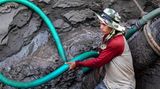Arbeiter hantiert beim Entladen eines Baggerschiffs mit schwerem Gerät