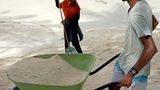 2 Menschen mit Schubkarre im Sand