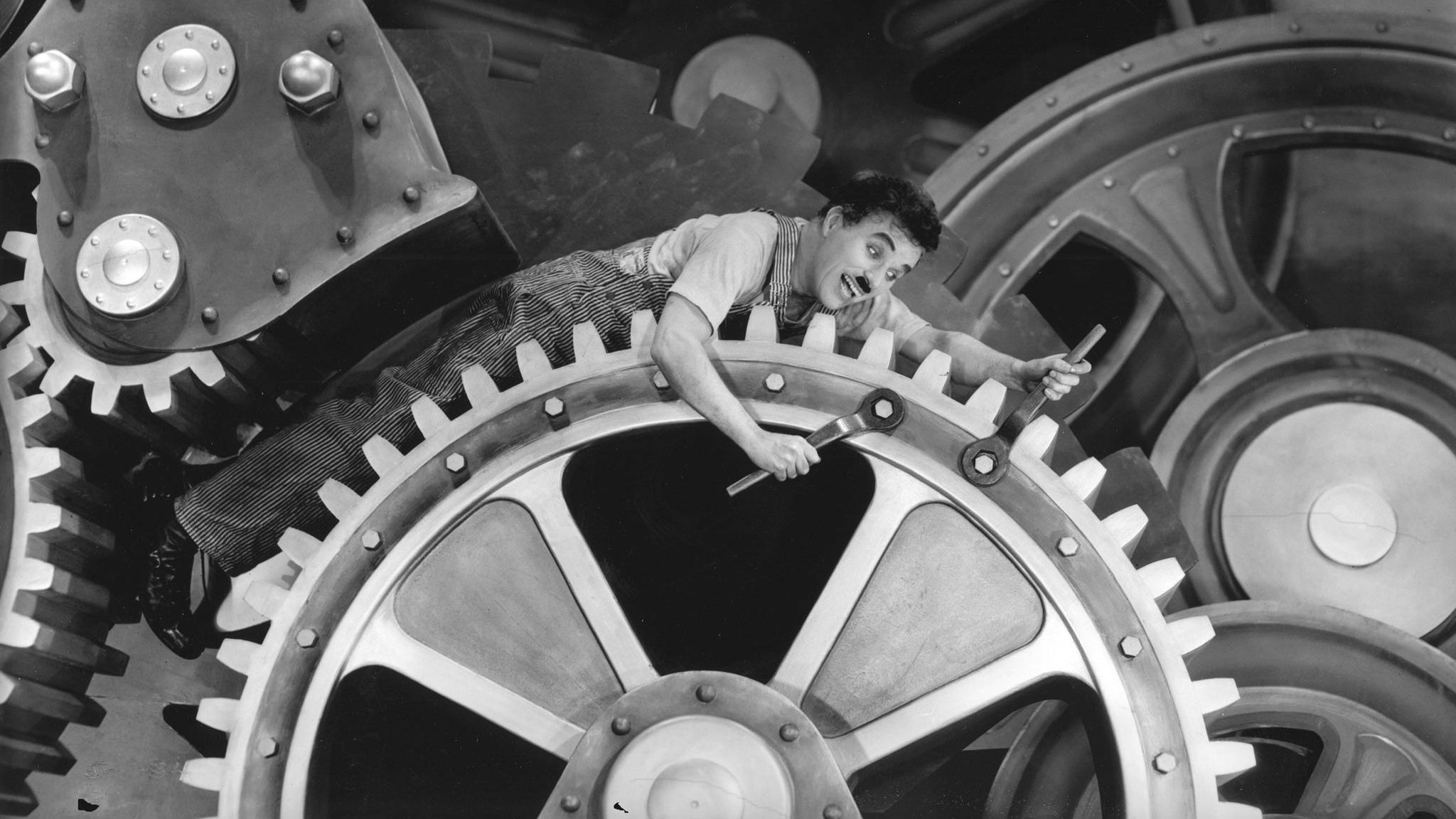 Szene aus Charlie Chaplins Film "Modern Times" von 1936, in der er auf einem Zahnrad liegt