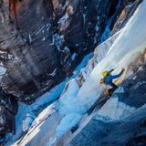Eine Person klettert einen vereisten Hang hinauf