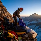 Zwei Männer mit ihren Schlafsäcken am Hang