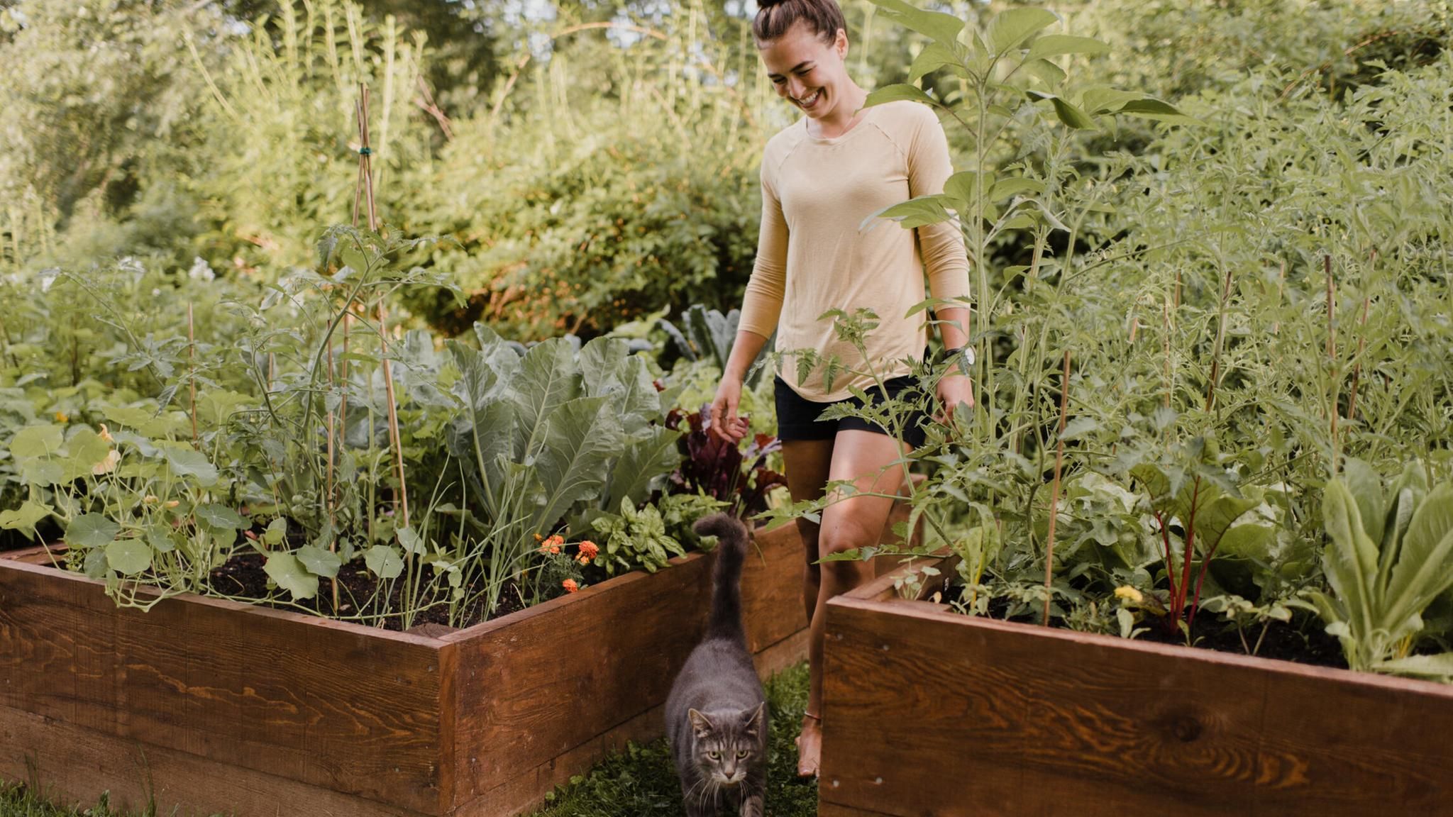 Frau im Garten zwischen ihren Hochbeeten