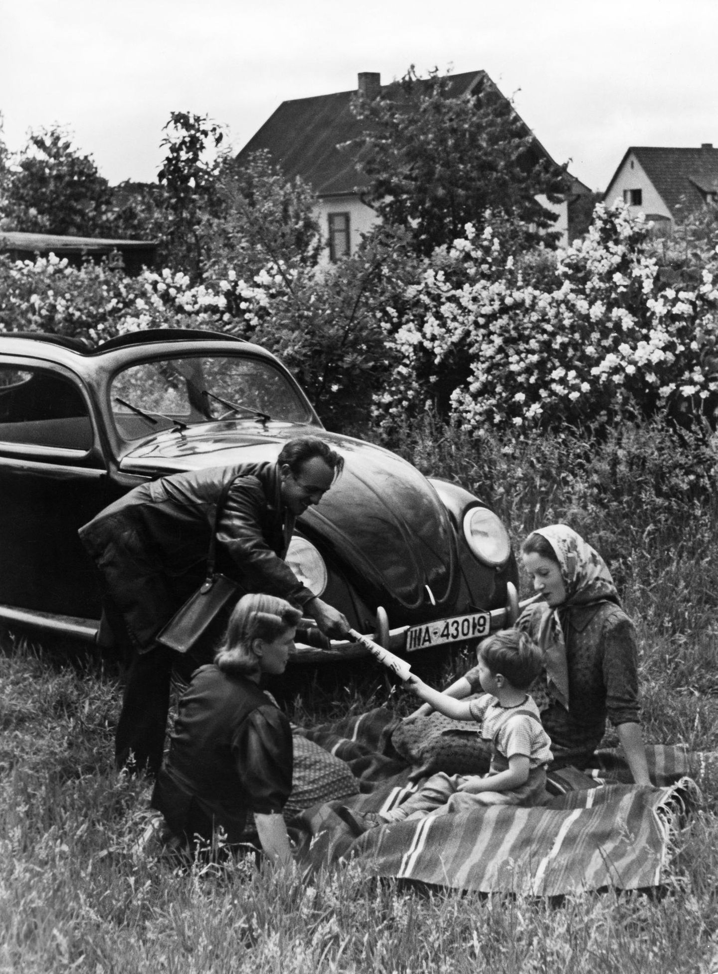 Eine Familie picknickt vor einem Volkswagen, 1940er-Jahre
