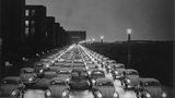 Käfer fahren über eine Straße in den 1950er-Jahren