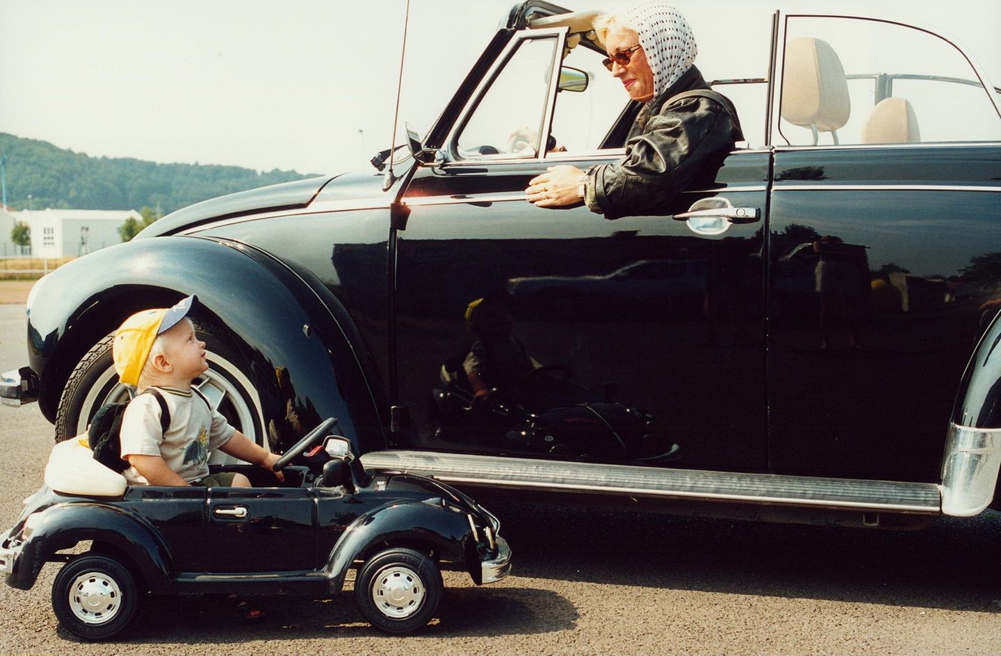 Der Käfer bleibt Kult Eine Frau in einem Käfer-Cabrio und ein kleines Kind in einem Käfer-Kinderauto