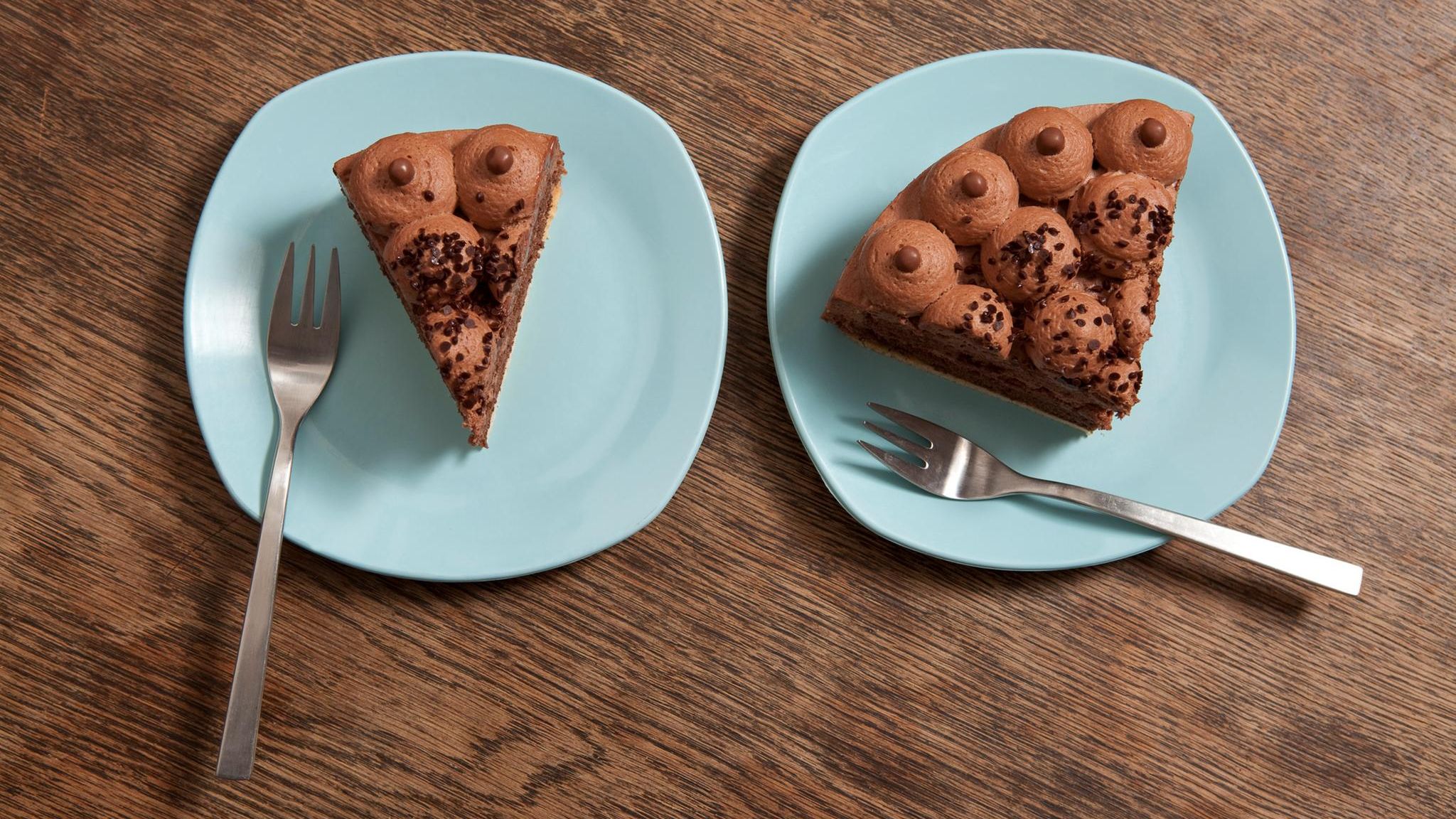 Zwei Teller mit unterschiedlich großen Stücken Kuchen