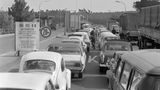 In der Zeit der deutschen Teilung bezeichnet der Transitverkehr die speziell geregelte Durchreise von Personen und auch Gütern durch das Gebiet der DDR. Einige wenige Transitstrecken verbinden damals den westlichen Teil Berlins mit der Bundesrepublik. An den innerdeutschen Grenzen werden die Pässe kontrolliert und der Reiseverkehr streng überwacht. Deshalb kommt es an den Kontrollpunkten, wie hier in Babelsberg 1969, häufig zu längeren Staus. Erst ab 1972 erleichtert ein Transitabkommen den Verkehr zwischen der BRD und West-Berlin deutlich.