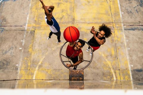 Drei Basketballspieler bespielen einen Korb