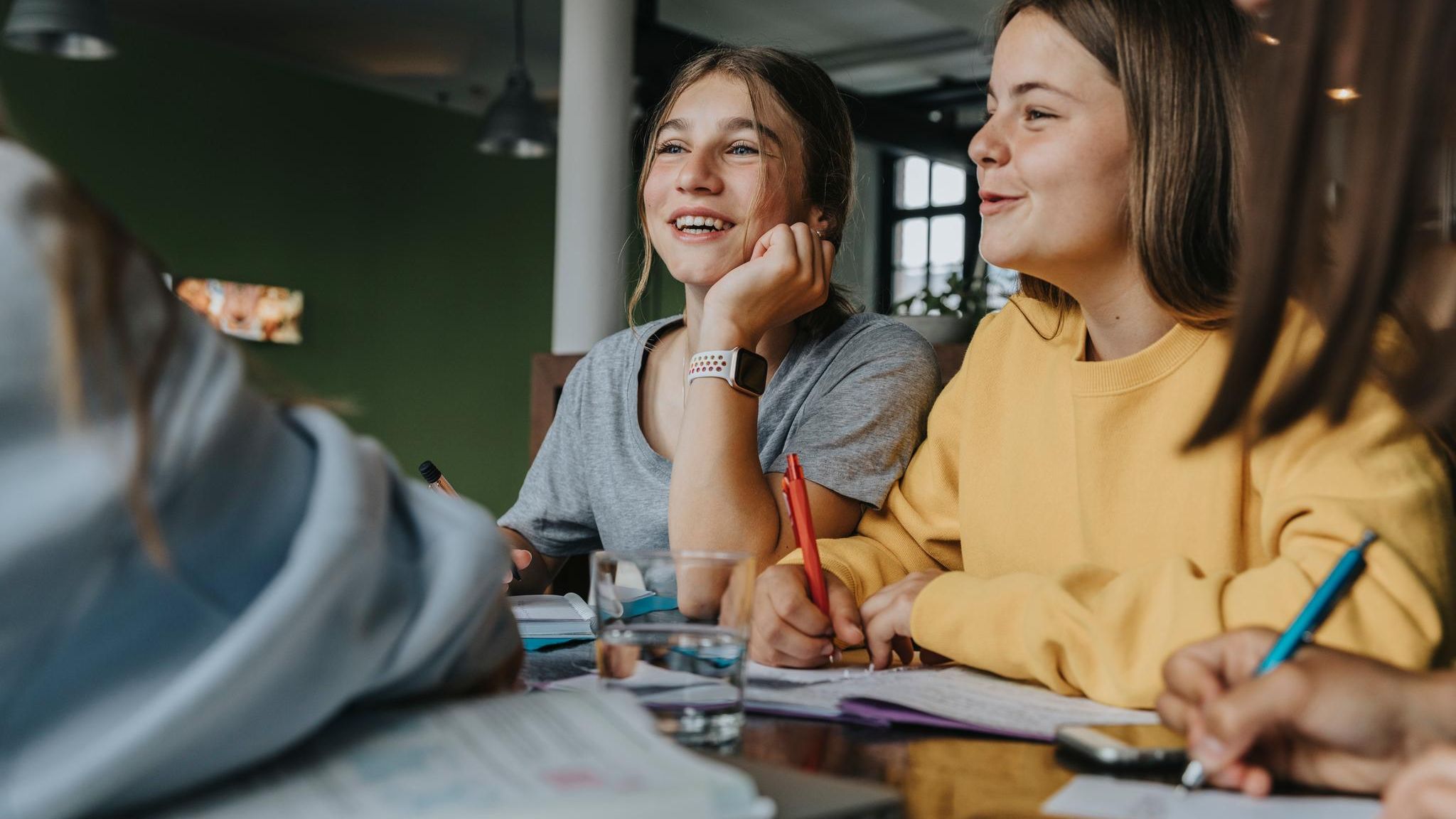 Jugendliche sitzen an einem Tisch und pauken gemeinsam Lernstoff