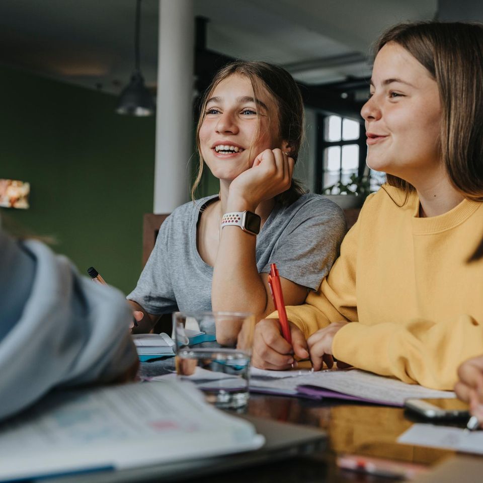 Jugendliche sitzen an einem Tisch und pauken gemeinsam Lernstoff