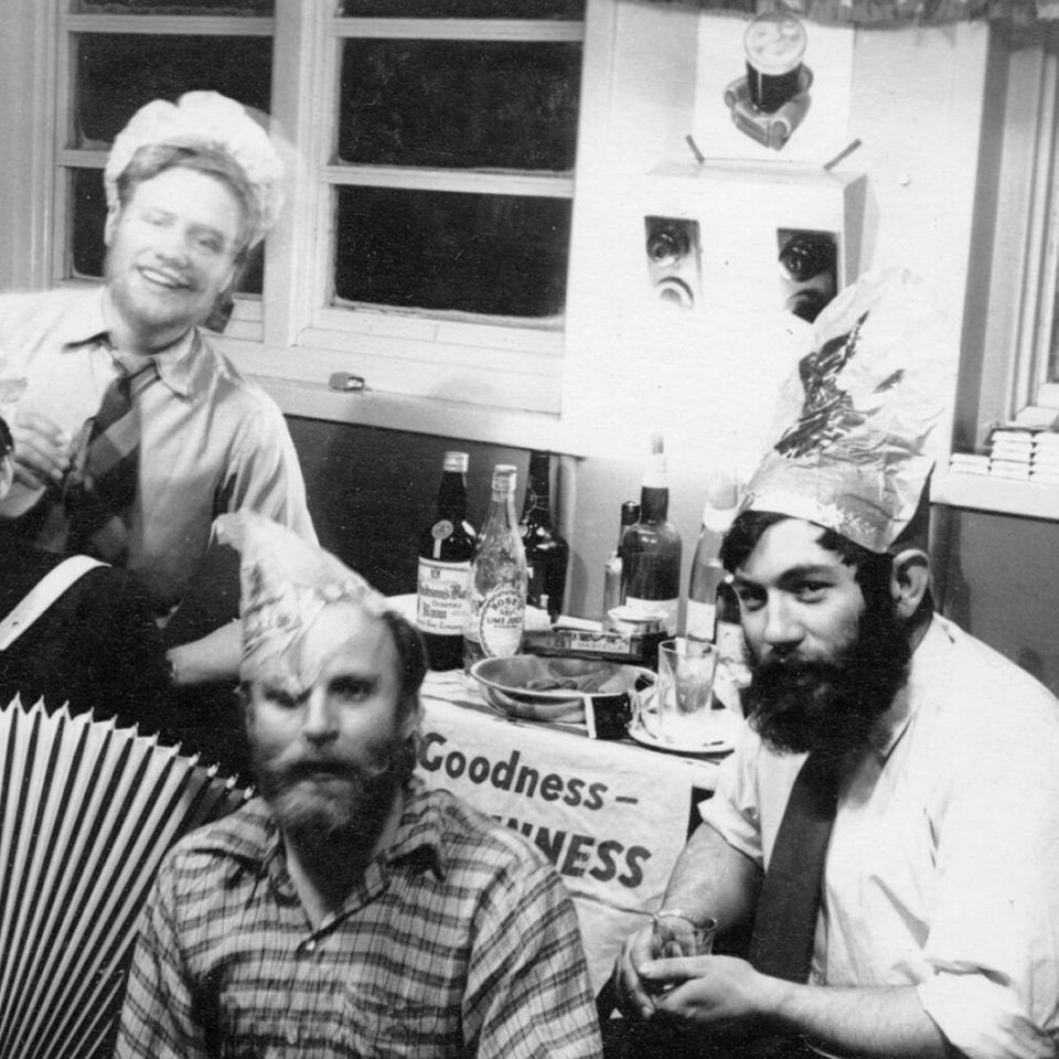 Schwarz-Weiß Foto einer Gruppe von fünf Männern mit einem Akkordeon, die gemeinsam feiern.