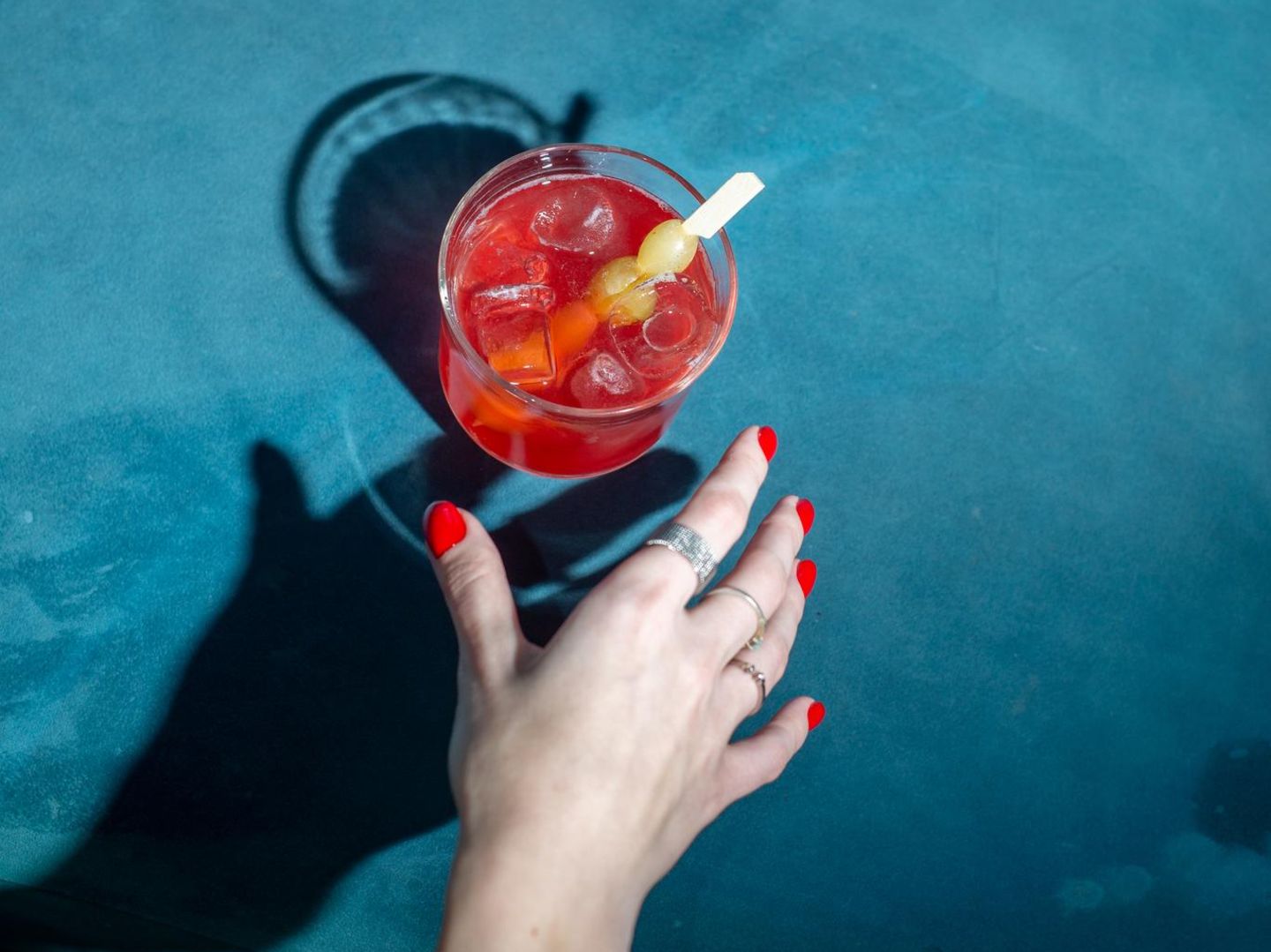 Frauenhand greift nach einem Cocktailglas