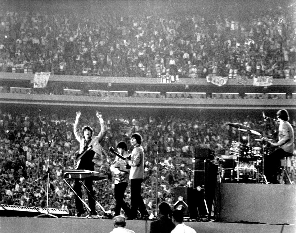 Schwarz-Weißfoto, Teleaufnahme: Die Beatles auf der Bühne des Shea Stadium während eines Konzerts