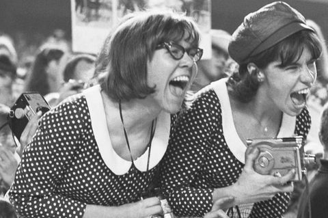 Schwarz-Weißfoto: Zwei weiblich Fans in identischen Outfits kreischen während eines Konzerts der Beatles, 1965