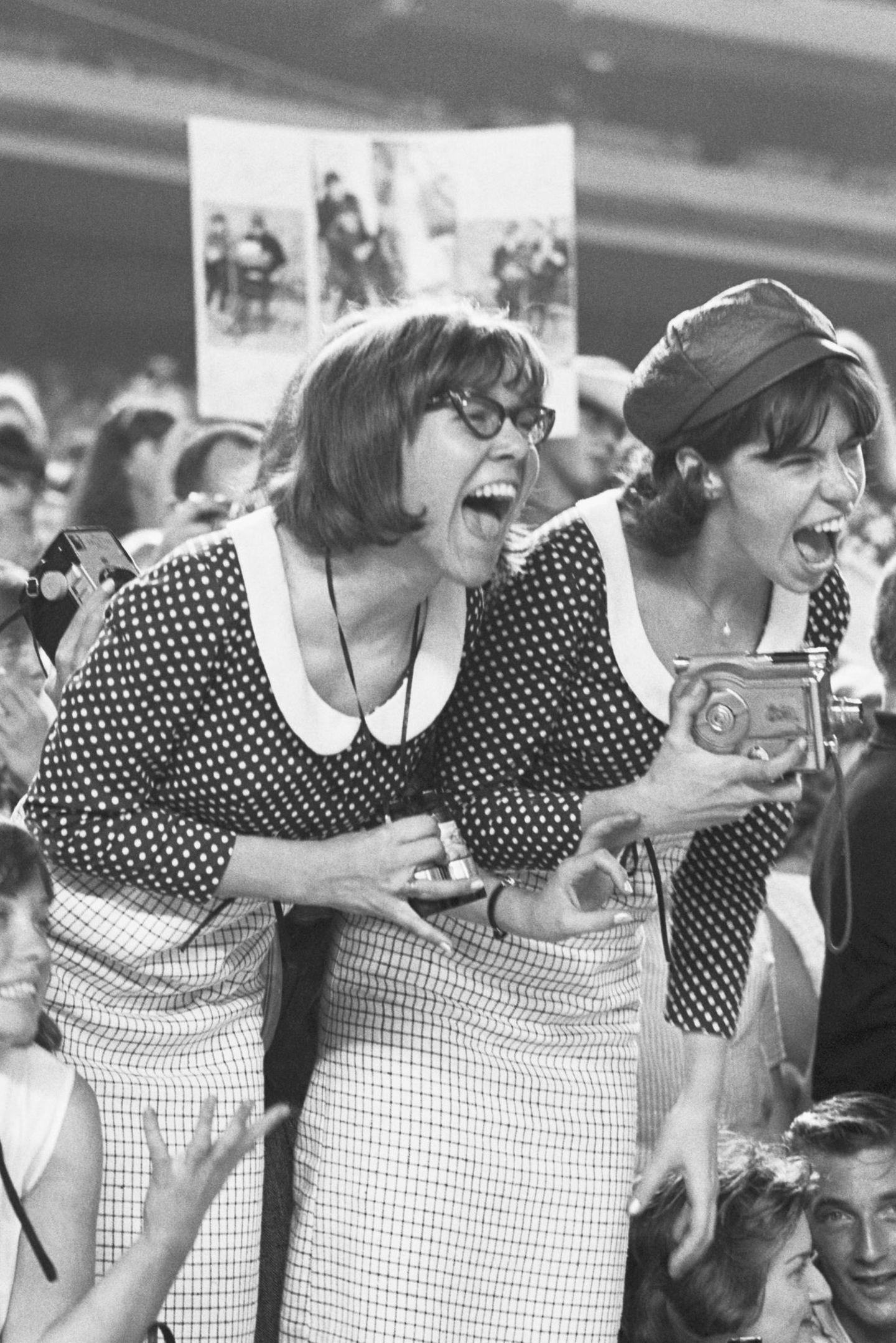 Schwarz-Weißfoto: Zwei weiblich Fans in identischen Outfits kreischen während eines Konzerts der Beatles, 1965