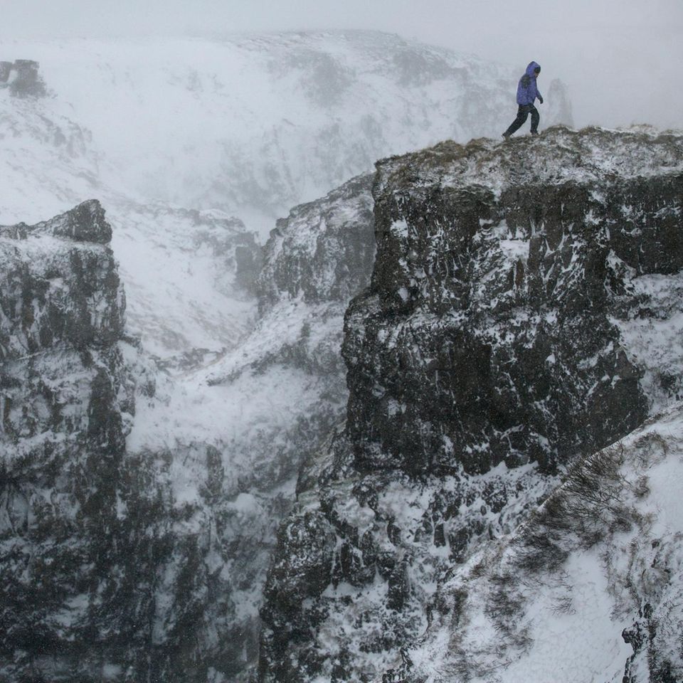 Wanderer in schroffer, schneebedeckter Gebirgslandschaft