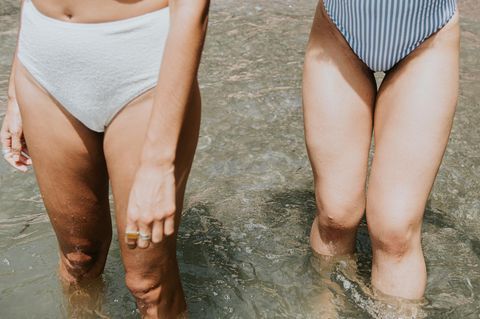 Zwei Frauen im Bikini kühlen sich die Beine im Wasser