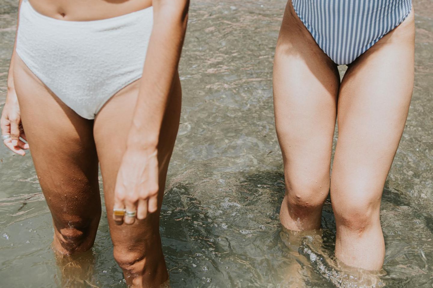 Zwei Frauen im Bikini kühlen sich die Beine im Wasser