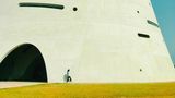 Harmonische Farbgebung, interessanter Linienverlauf, überraschendes Gebäude, Architektur, die durch die Person ins Größenverhältnis gerückt wird, surrealer Charakter 