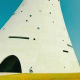 Harmonische Farbgebung, interessanter Linienverlauf, überraschendes Gebäude, Architektur, die durch die Person ins Größenverhältnis gerückt wird, surrealer Charakter 