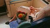 Geschichte passiert sofort im Kopf, wer bekommt die Blumen? Freudige Erwartung der abgebildeten Person sichtbar, ohne dass man das Gesicht sehen muss, Moment des Augenblicks, im Vorübergehen gesehen, kleinen Momente im Alltag, die schnell untergehen festgehalten