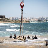Männer bergen Statue aus dem Wasser
