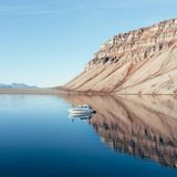 Während des Polartags gut zu schlafen ist gar nicht so einfach. Eine Schlafmaske hilft – manchmal. Doch gegen das helle Licht, das selbst um Mitternacht durch Vorhänge und Fenster dringt, kämpft man meist vergeblich. An diesem Junitag zeigt das Thermometer warme acht Grad, der Himmel ist klar, und die Sonne scheint – Sommer auf Spitzbergen. Perfekt für eine Bootstour, um die stille Schönheit des Fjords zu genießen. Immer im Gepäck: Kaffee, Snacks und alle notwendigen Ausrüstungsgegenstände, wie Leuchtpistole, Funkgerät, Schusswaffe und Satellitentelefon.    