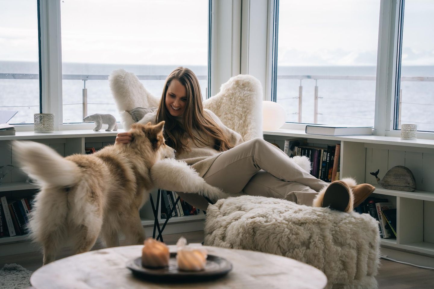 Zuhause zwischen Meer und Permafrost Wenn draußen der eisige Wind über Longyearbyen fegt, knistert in Cecilia Blohmdahls Haus der Ofen. Ihr Heim am Stadtrand hat sie mit ihrem Partner vergrößert – heute ist es doppelt so groß wie früher. Ein Ausbau, der Geduld und Nerven kostete. Auf Spitzbergen baut man nicht einfach. Hier wartet man auf Genehmigungen, kämpft mit der Logistik – und stellt Häuser auf Pfähle, um sie im gefrorenen Boden zu verankern. Denn die Landfläche besteht zum größten Teil aus Permafrost oder Dauerfrostboden. Blohmdahl aber hatte Glück. Ihr Grundstück liegt zwar nah am Wasser, doch der Boden darunter ist massiver Fels. Deshalb droht kein Absacken oder Abrutschen ins Meer – das Haus wird bleiben, wo es steht.