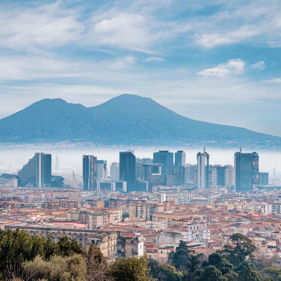 Die Skyline einer Stadt ragt aus Nebel hervor. Im Hintergrund erstreckt sich ein Berg