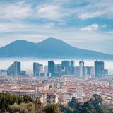 Die Skyline einer Stadt ragt aus Nebel hervor. Im Hintergrund erstreckt sich ein Berg