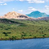 Hinter einer grünen Wiese ragt der Taal-Vulkan empor