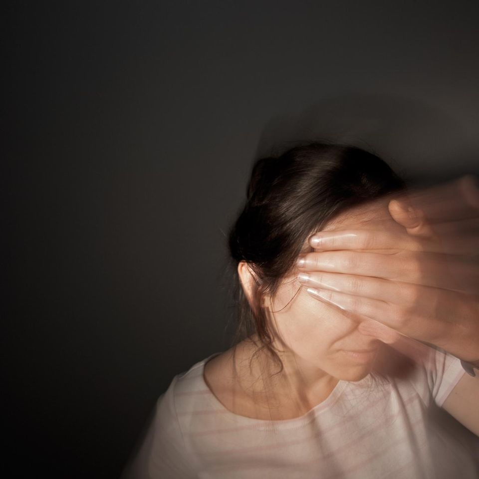 Frau greift sich an den Kopf