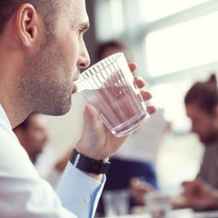 Geschäftsmann trinkt ein Glas Wasser