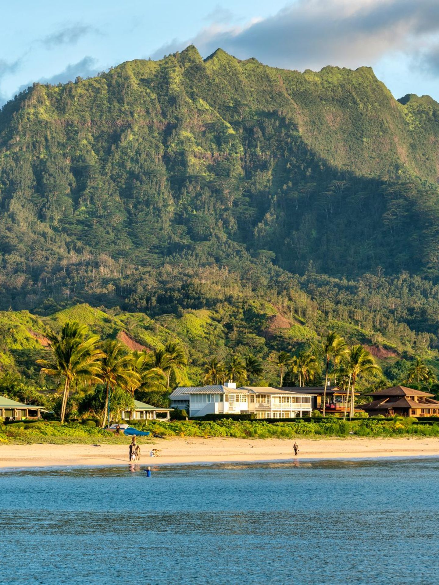 Ein Haus am Sandstrand mit einer grünen Berglanschaft im Hintergrund