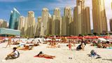 Menschenmenge am Strand mit Hochhäusern im Hintergrund