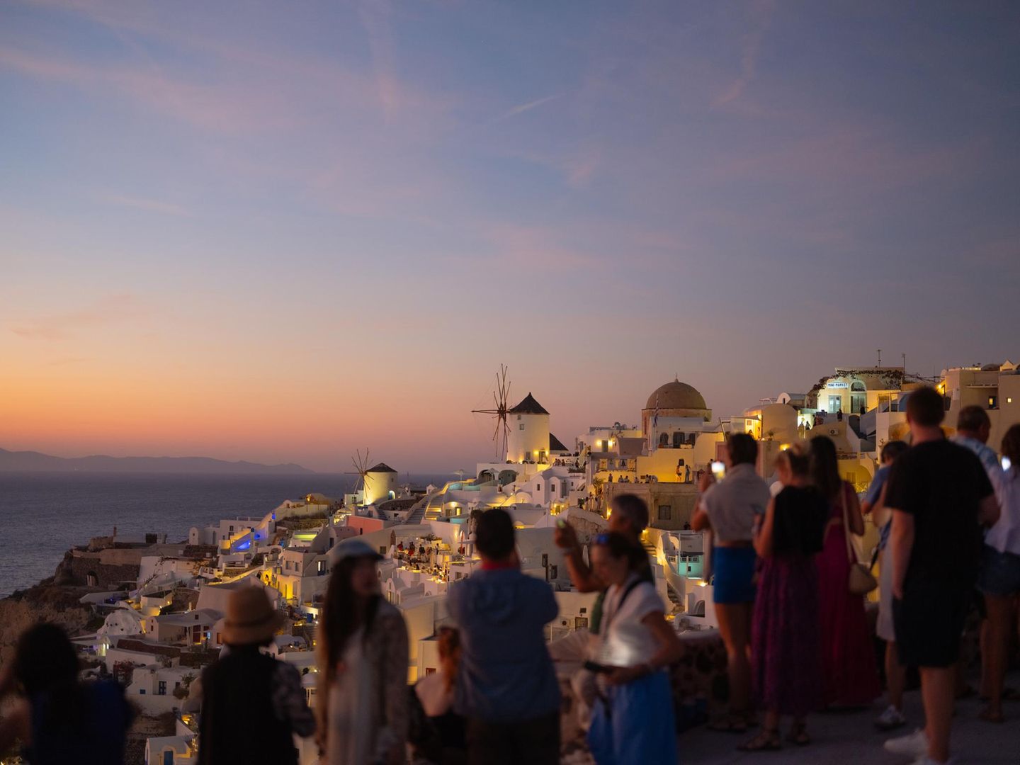 Santorin: Griechenland wie im Reisekatalog Menschenmenge, die bei Sonnenuntergang über die Dächer guckt