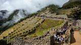 Schlange an Menschen auf den Wegen einer Ruine am Berg zu Machu Picchu