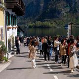Eine Gruppe Menschen bedeckt die Sraße, um zu fotografieren. Im Hintergrund Wasser und Berge