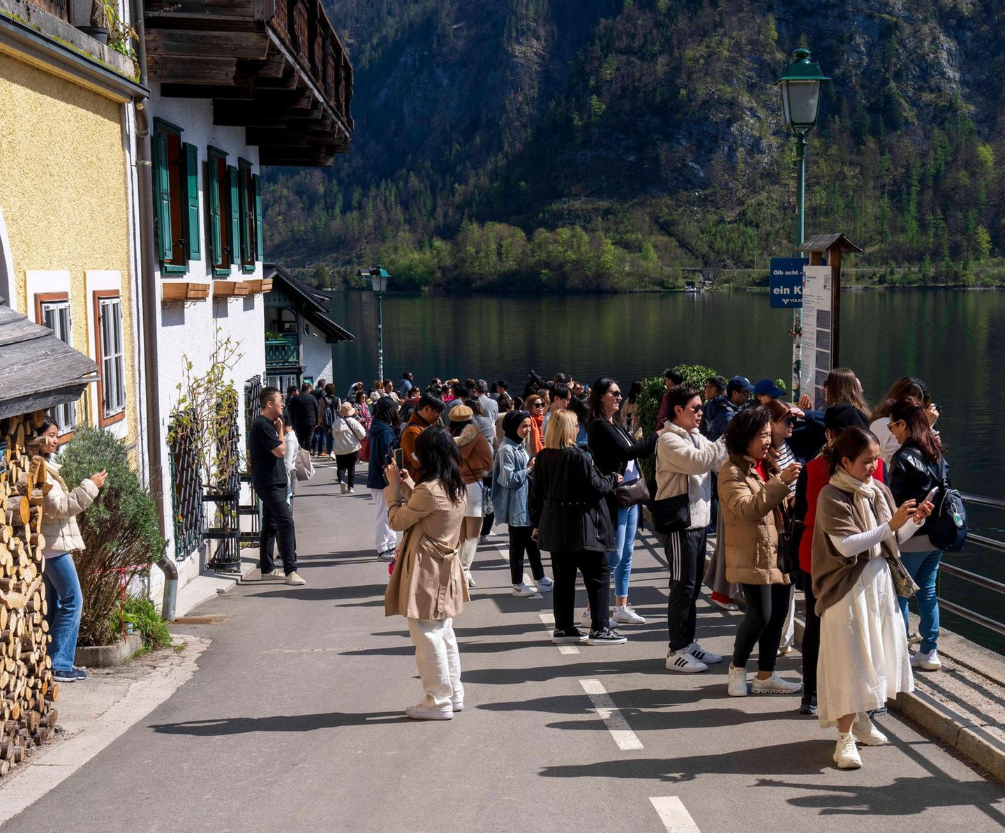 Hallstatt: Zu viel des Ruhms Eine Gruppe Menschen bedeckt die Sraße, um zu fotografieren. Im Hintergrund Wasser und Berge