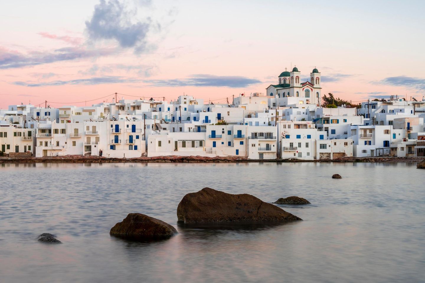 Paros: Kykladen-Charme trifft Gelassenheit Weiße Häuser am Wasser in Paros, der Himmel in rosa-Tönen