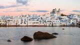 Weiße Häuser am Wasser in Paros, der Himmel in rosa-Tönen