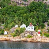 Blick auf den Leuchtturm Odderøya Fyr, dahinter Felsen und Bäume