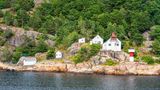 Blick auf den Leuchtturm Odderøya Fyr, dahinter Felsen und Bäume