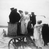 Personen stehen auf hölzernem Wagen am Strand