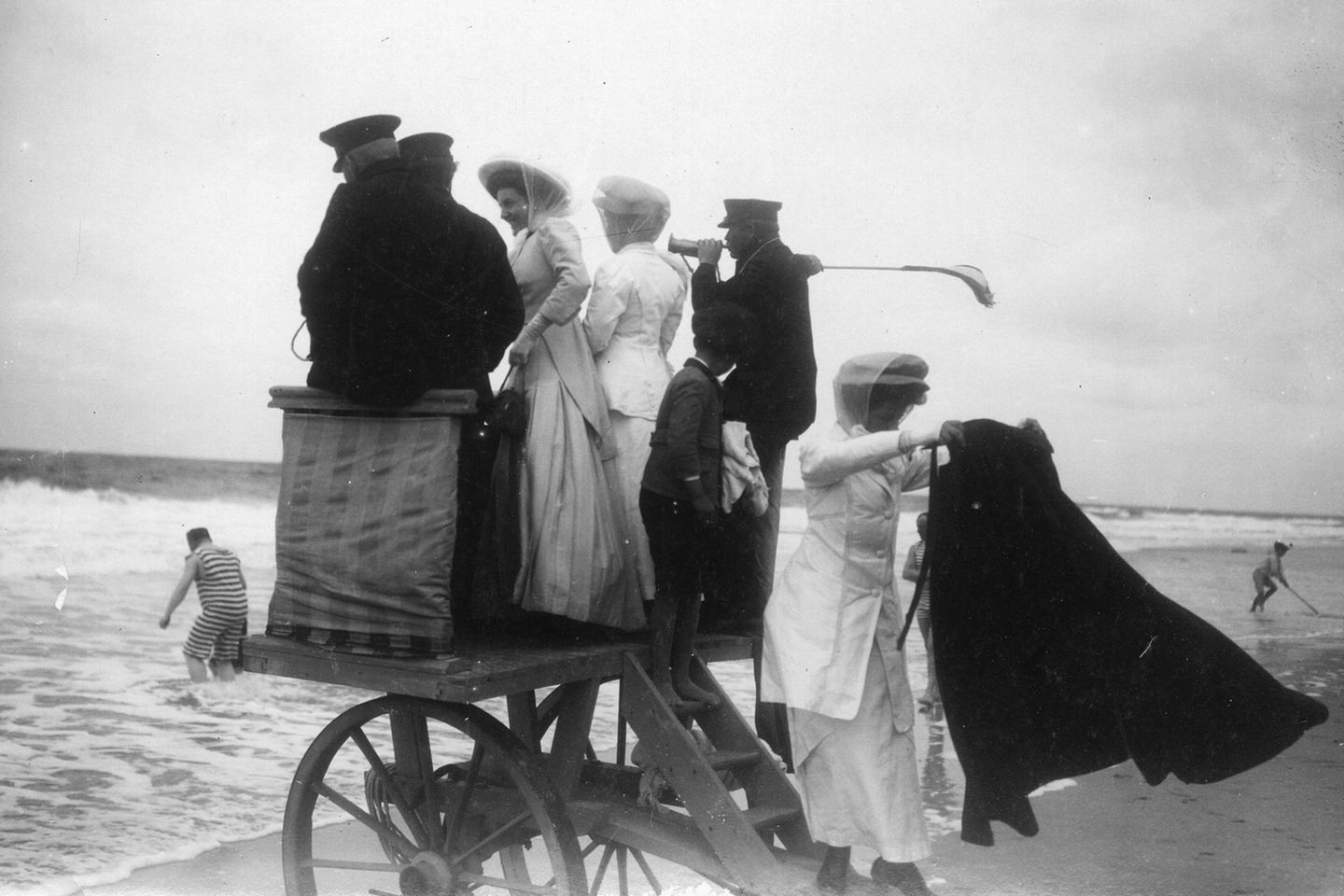 Personen stehen auf hölzernem Wagen am Strand