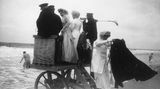 Personen stehen auf hölzernem Wagen am Strand