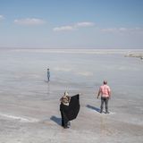 Drei Menschen stehen an einem Salzsee bei Ghom