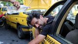 Eine person lehnt sich aus einem Taxi und wird aufgrund von Hitze in Teheran mit einer Flasche Wasser übergossen