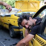 Eine person lehnt sich aus einem Taxi und wird aufgrund von Hitze in Teheran mit einer Flasche Wasser übergossen