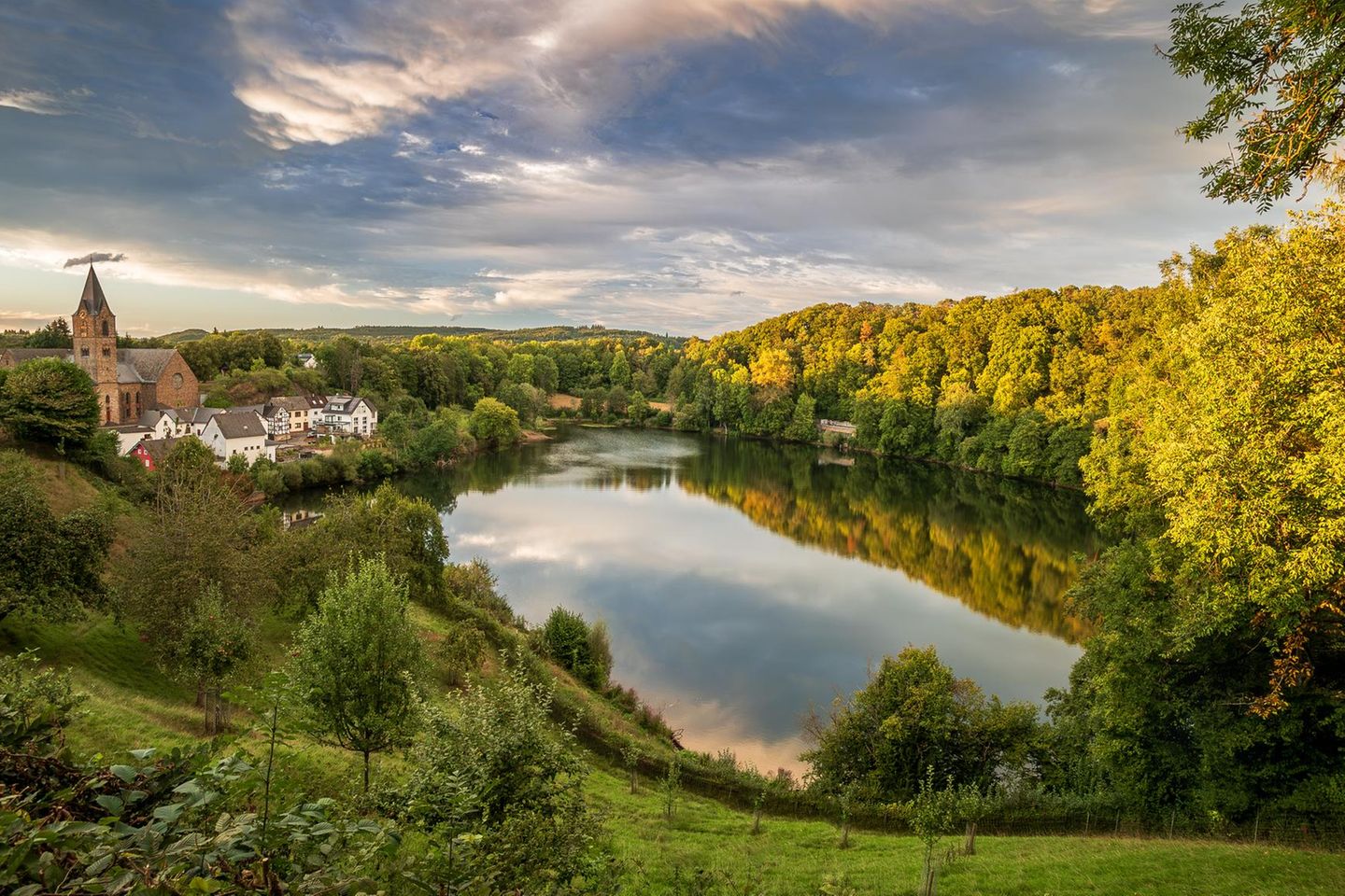 Elevated view of the Ulmener Maar and its shores, with the village of Ulmen at sunset, a volcanic lake and crater part of the Eifel National Park (Vulkaneifel) on the German volcanic route, an UNESCO Geopark, Daun - Rhineland-Palatinate - Germany.